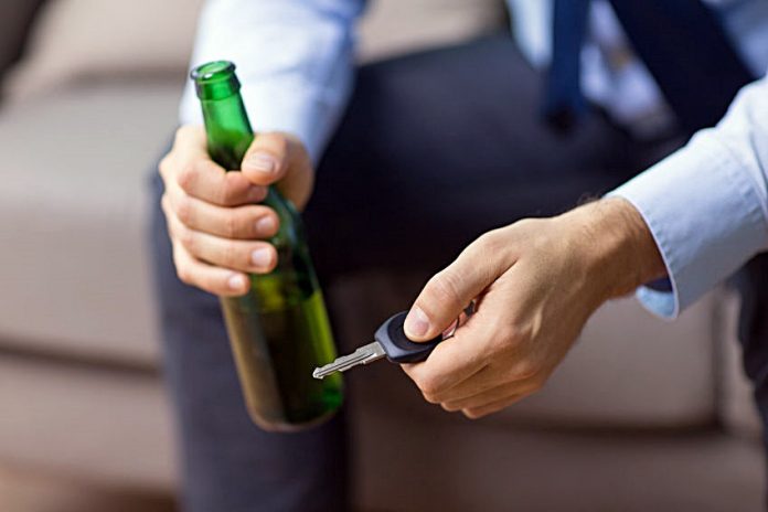 male driver hands holding beer bottle and car key